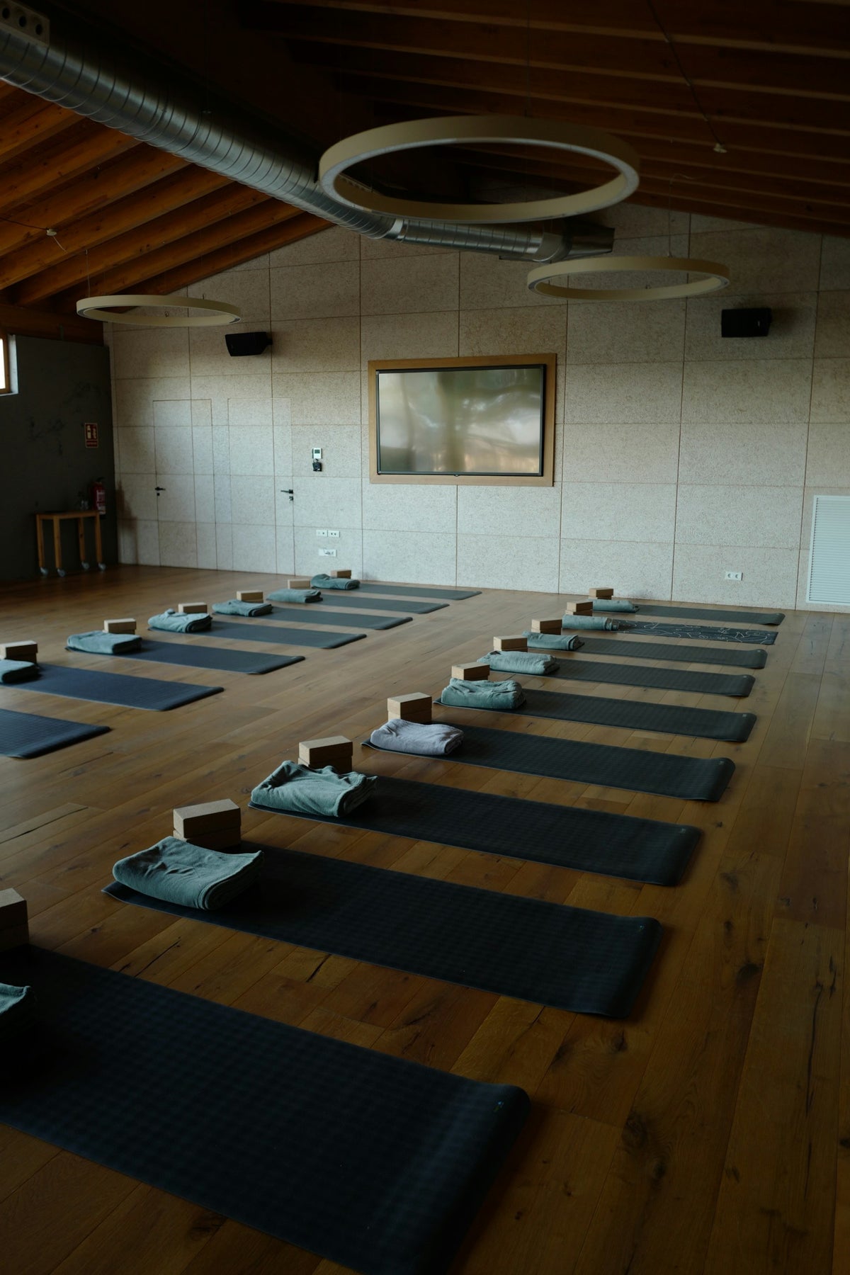 Rolled yoga mats and blocks on a light wood studio floor