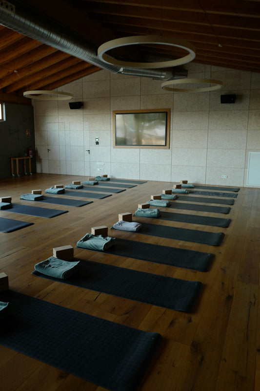 Rolled yoga mats and blocks on a light wood studio floor